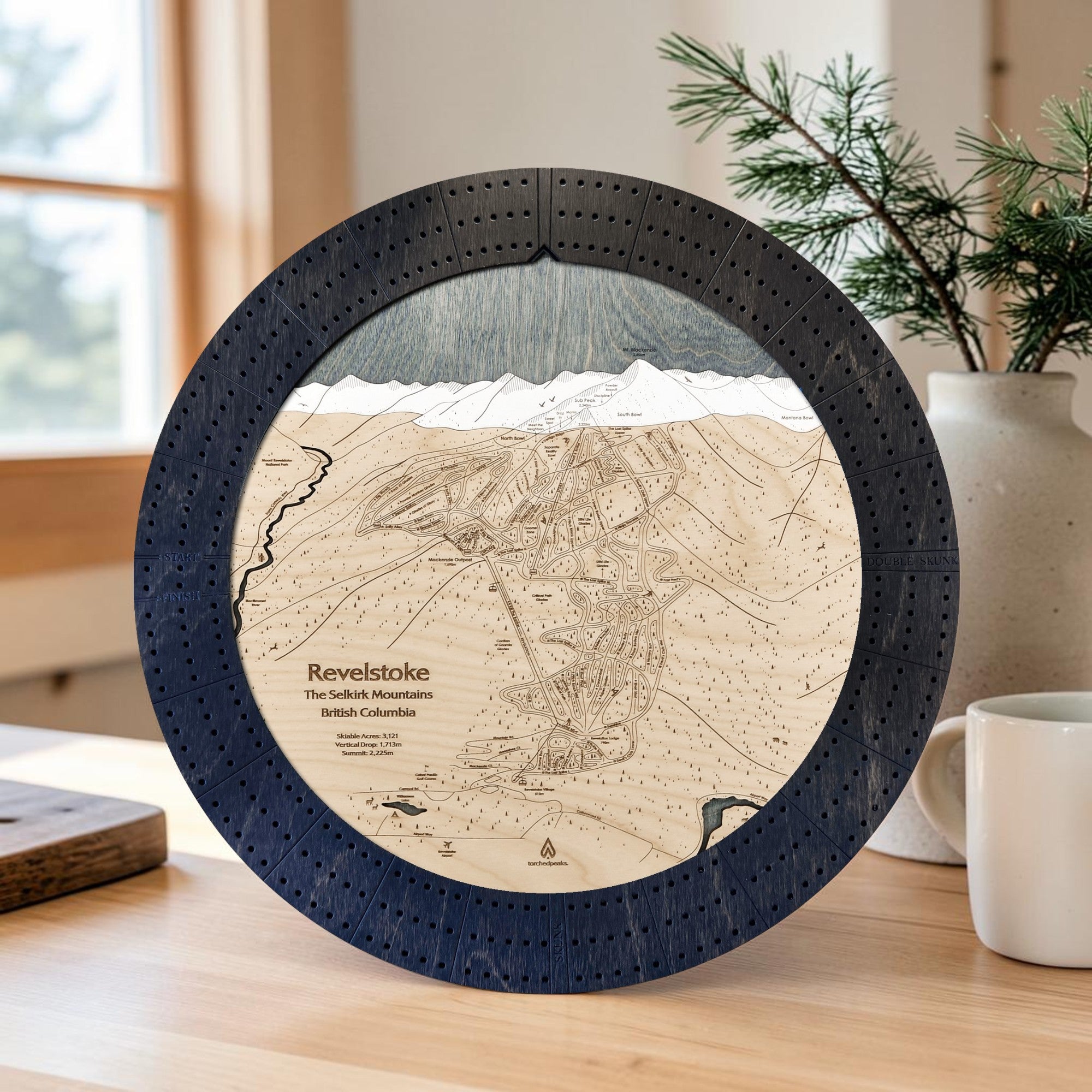 Matte Onyx Revelstoke ski trail map cribbage board displayed on a light wood table in a modern ski home.