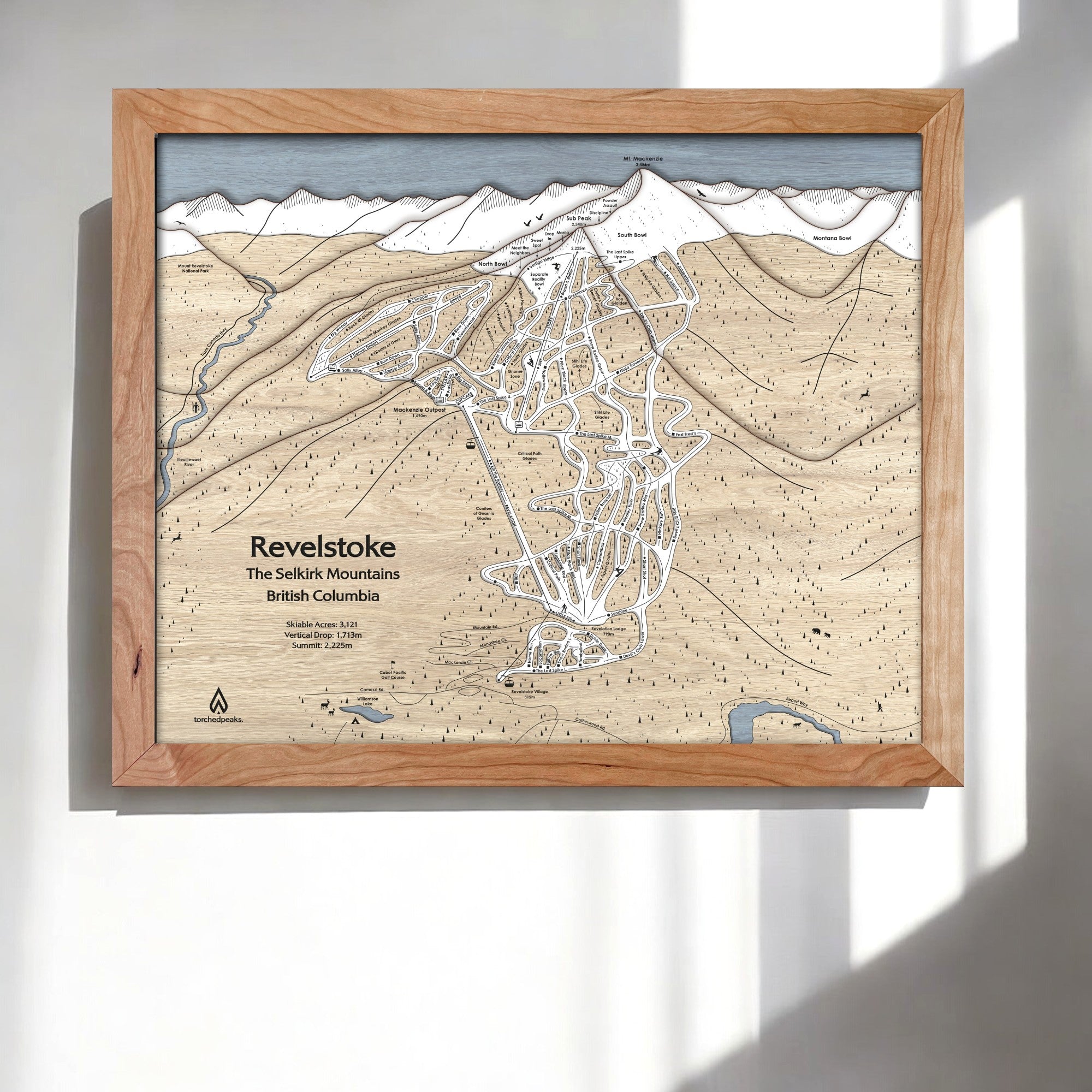 Framed 3D wood map of Revelstoke Ski Resort, British Columbia, on a white wall in a modern ski chalet.