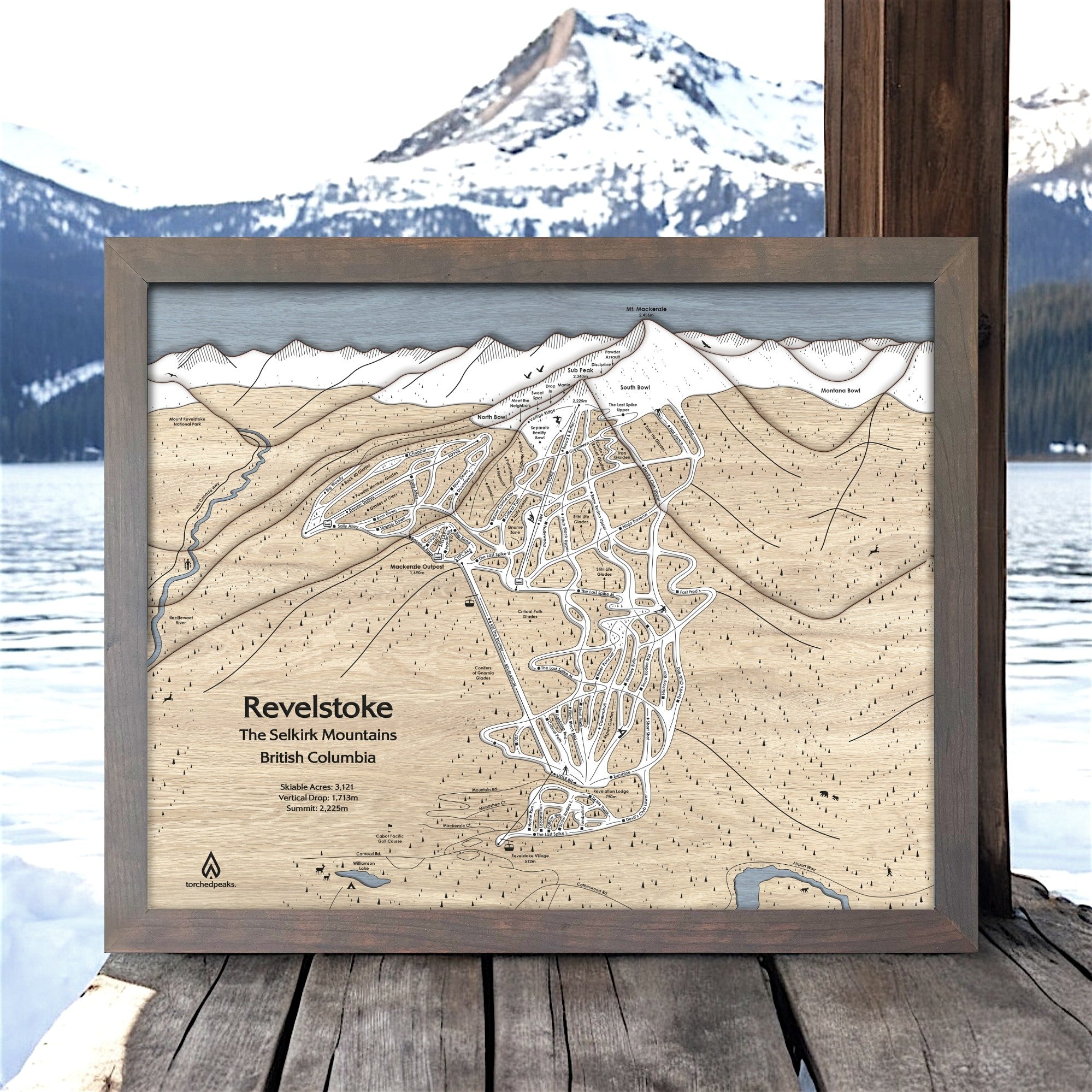 Framed wooden map of Revelstoke Mountain with a mountainous landscape in the background