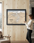 Woman looking at a framed map of Revelstoke Ski Resort set in a cozy rustic ski cabin.