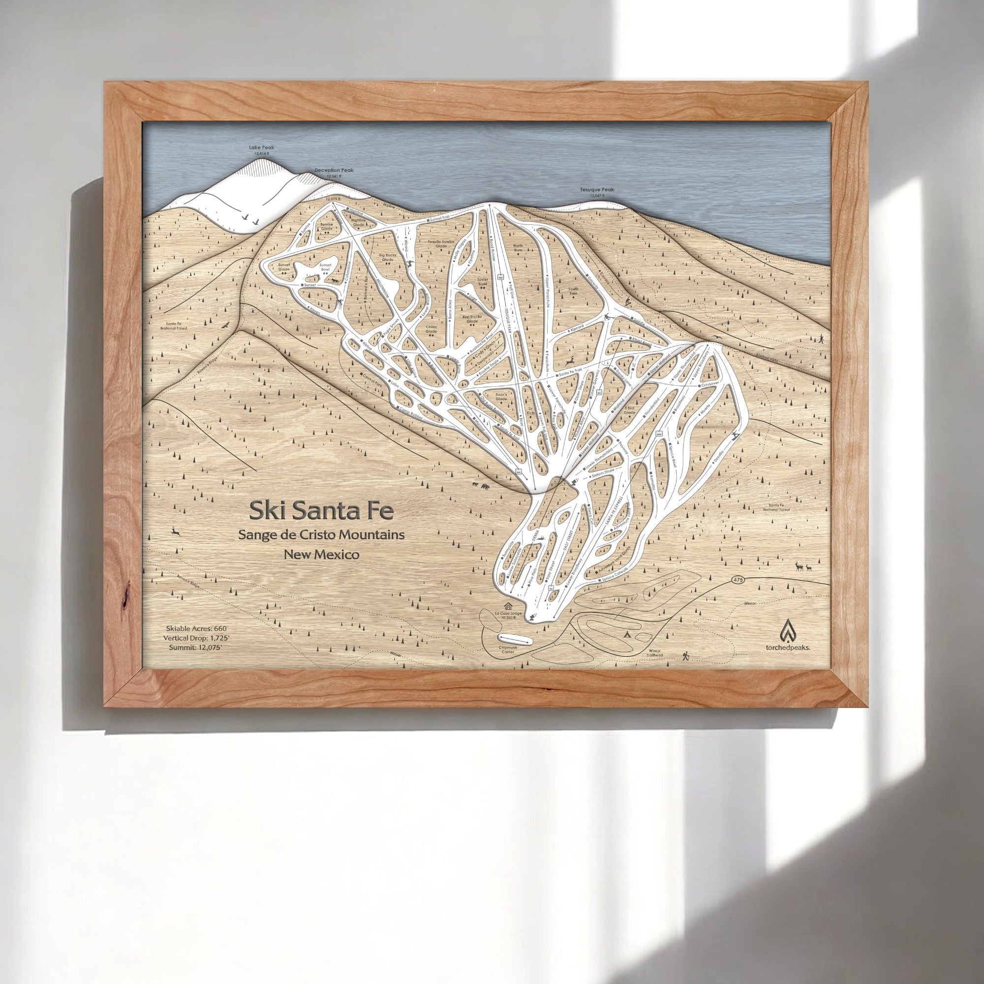 3D Wooden framed trail map of Ski Santa Fe on a white wall inside a modern ski house. 