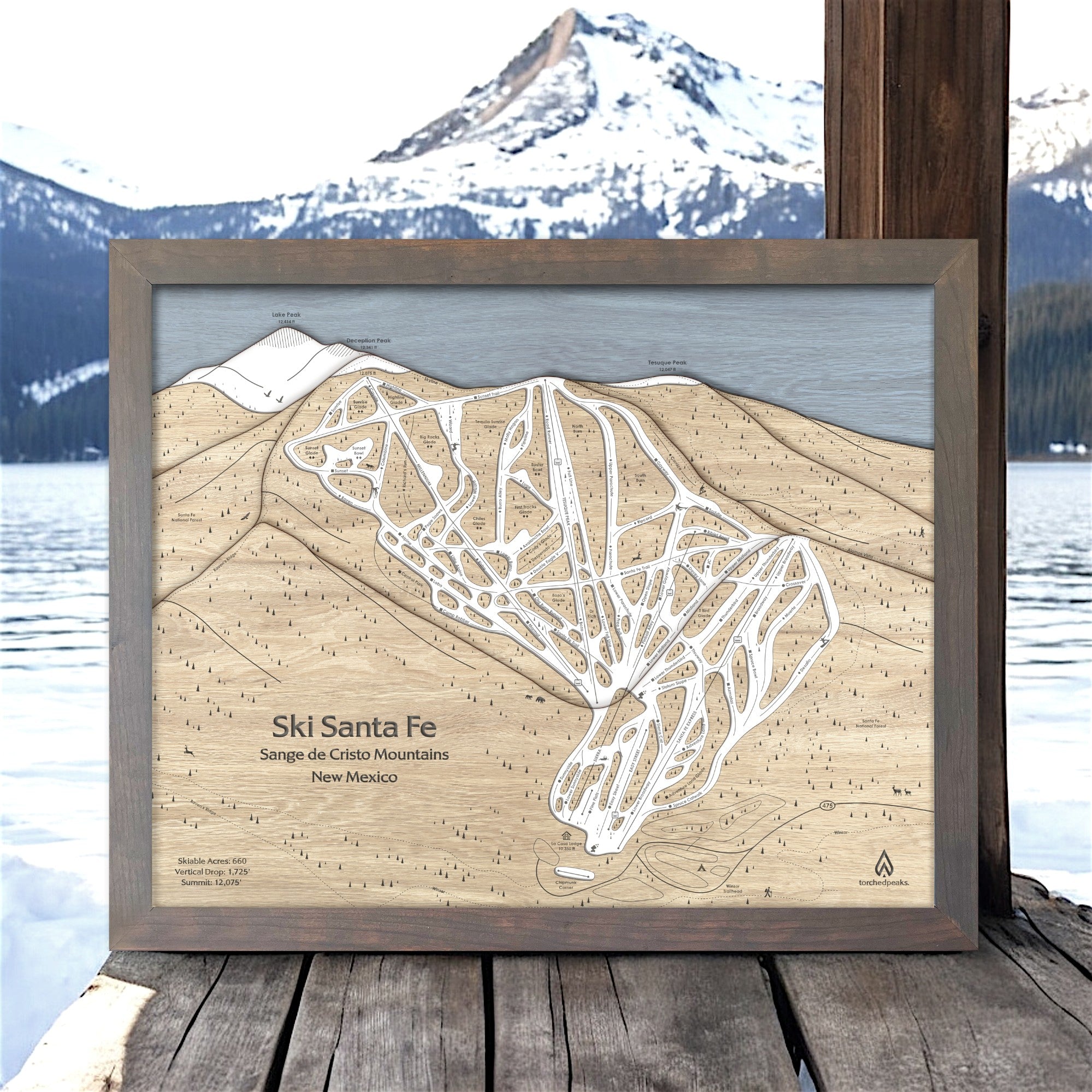 Framed wooden map of Ski Santa Fe with a mountainous background