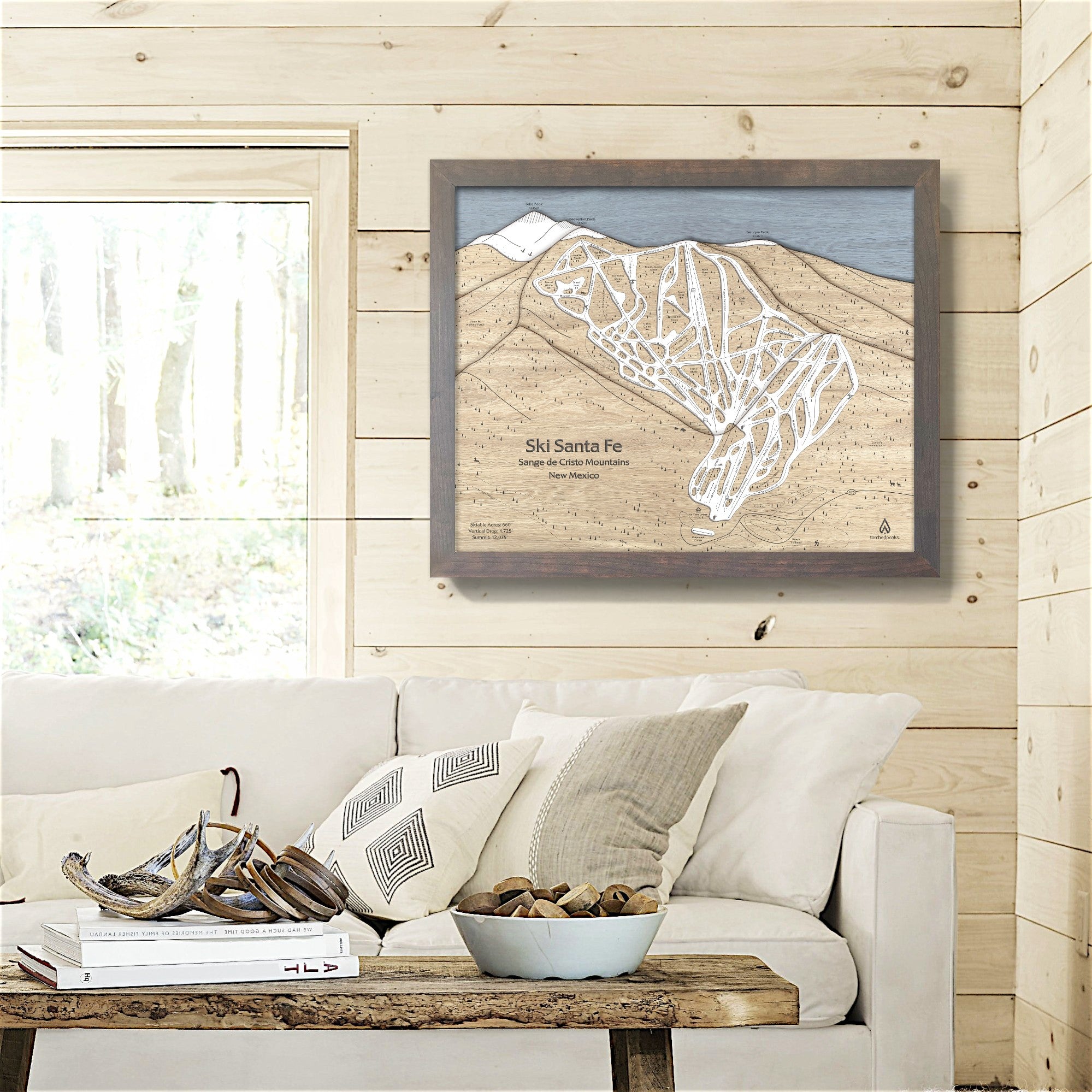 Framed ski trail map of Ski Santa Fe above a sofa in a living room inside a ski cabin. 