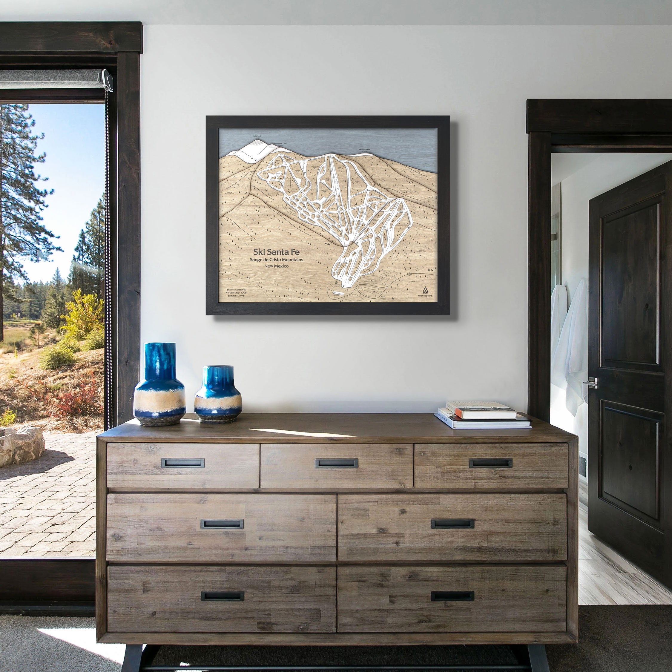 Framed artwork of Ski Santa Fe ski resort on a white wall inside a modern ski house. 