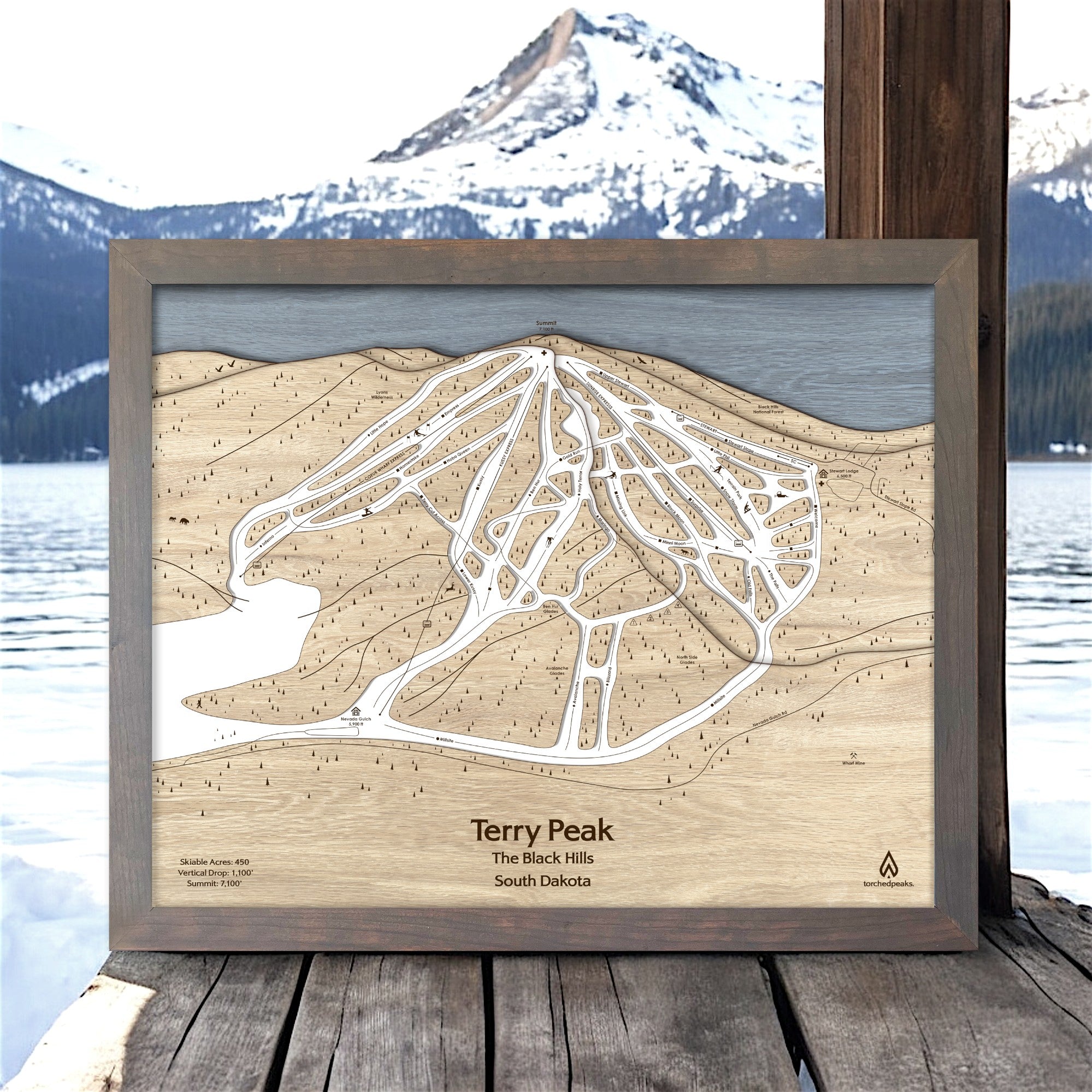 Wooden topographic map of Terry Peak in the Black Hills, South Dakota, with a scenic mountain background.