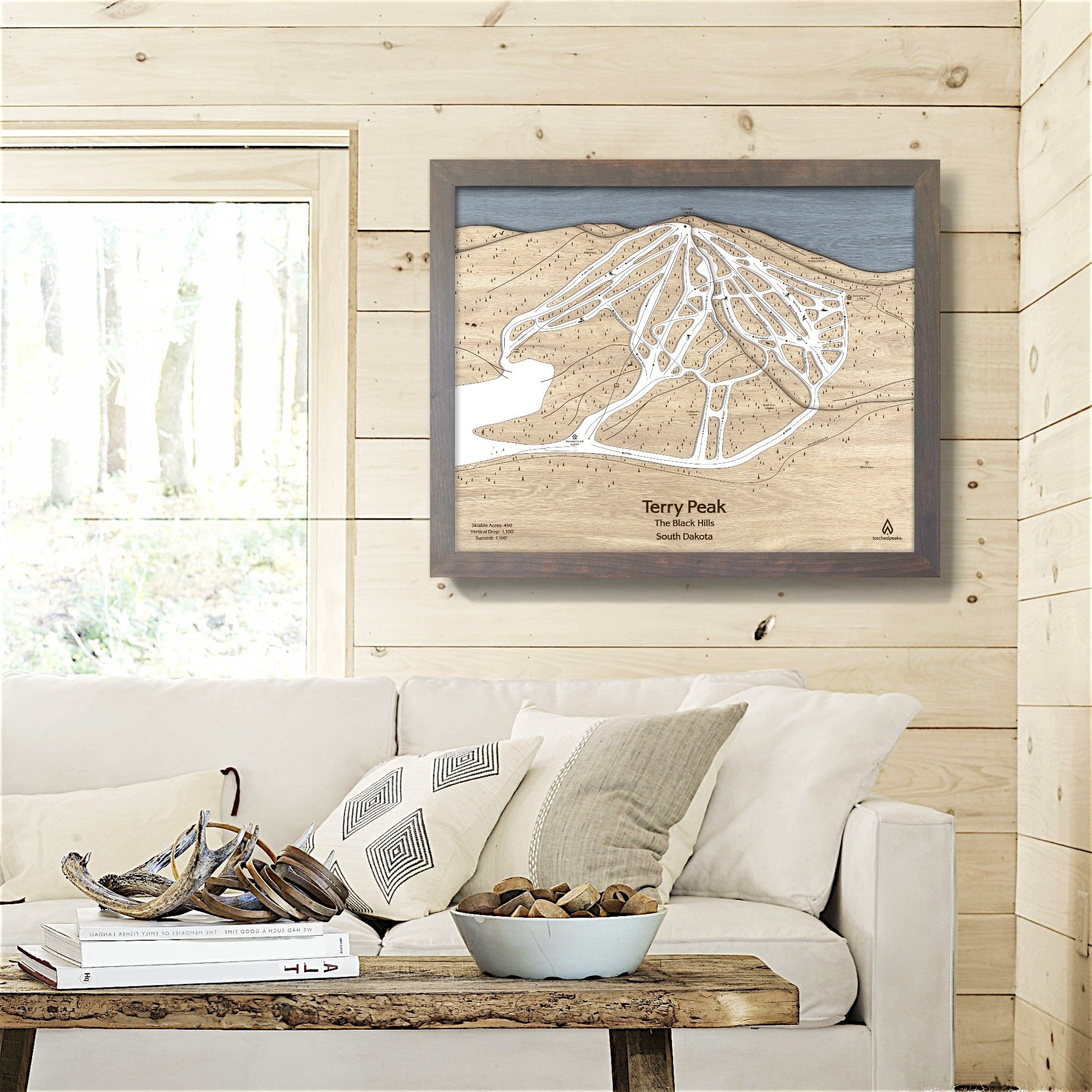 Framed 3d wood map of Terry Peak Ski Resort on a wall in a living room of a cozy skiing cabin. 
