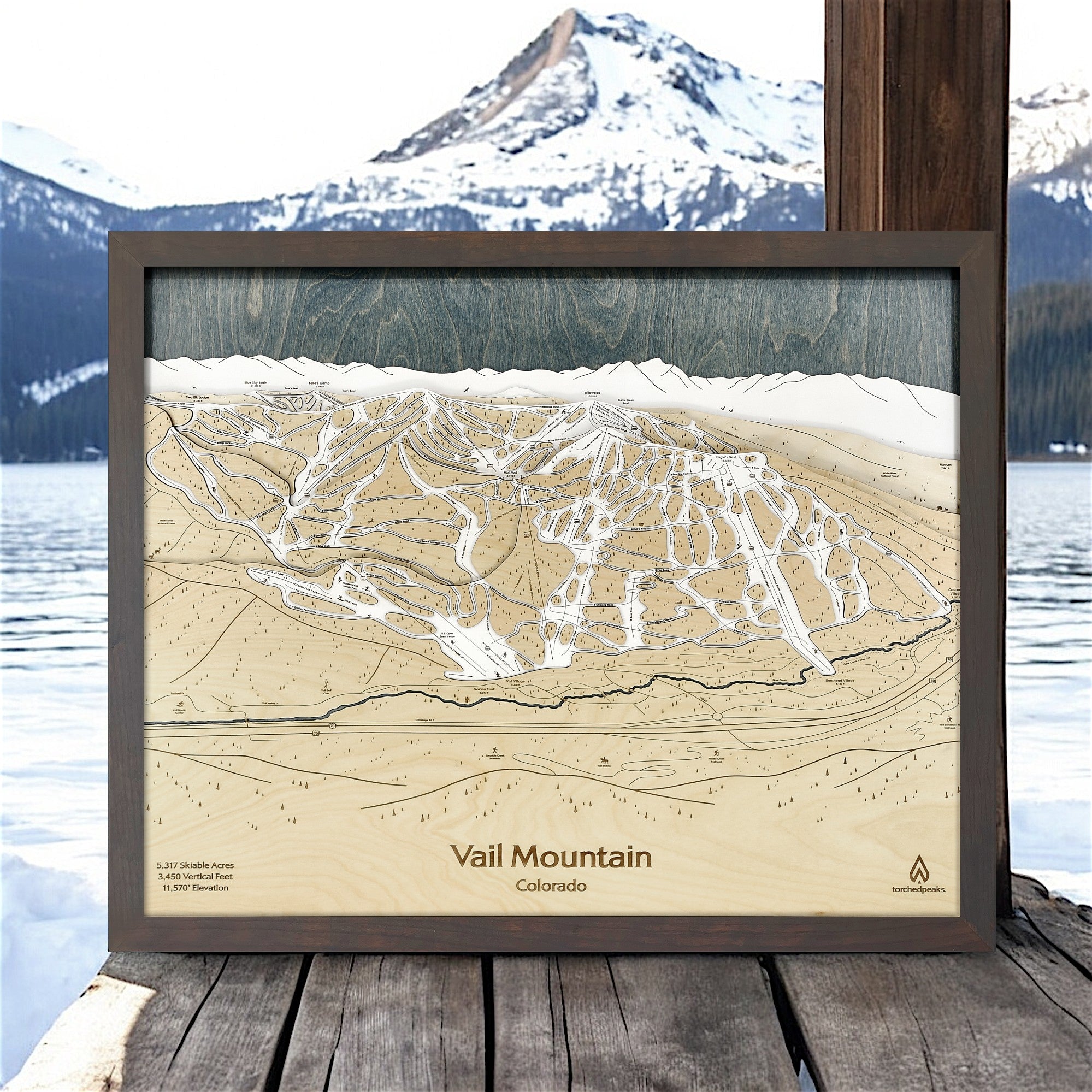 Wooden topographic map of Vail Mountain with a scenic mountain backdrop