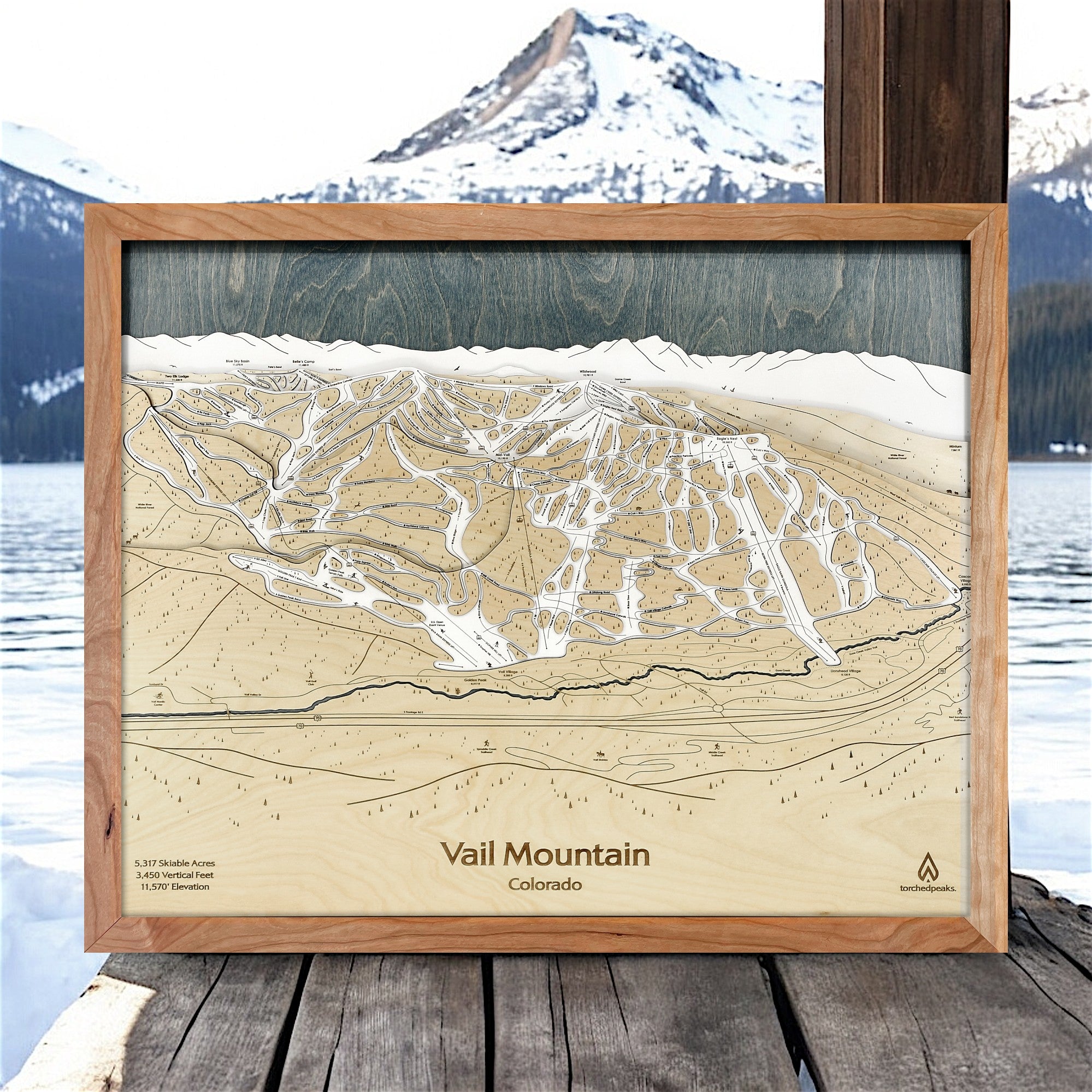 Wooden framed topographic map of Vail Mountain, Colorado with a mountainous landscape in the background.