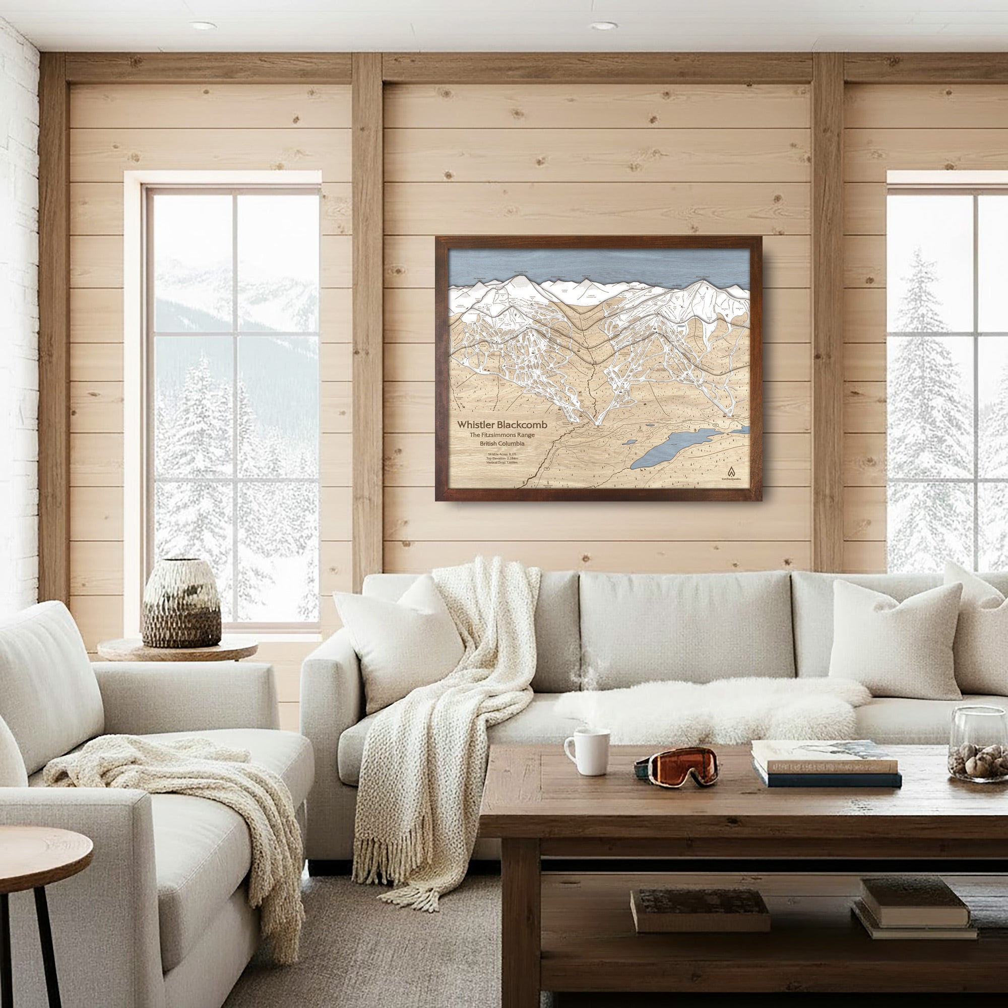 Framed Whistler Blackcomb wood ski map displayed above a white sofa in a bright, modern mountain living room