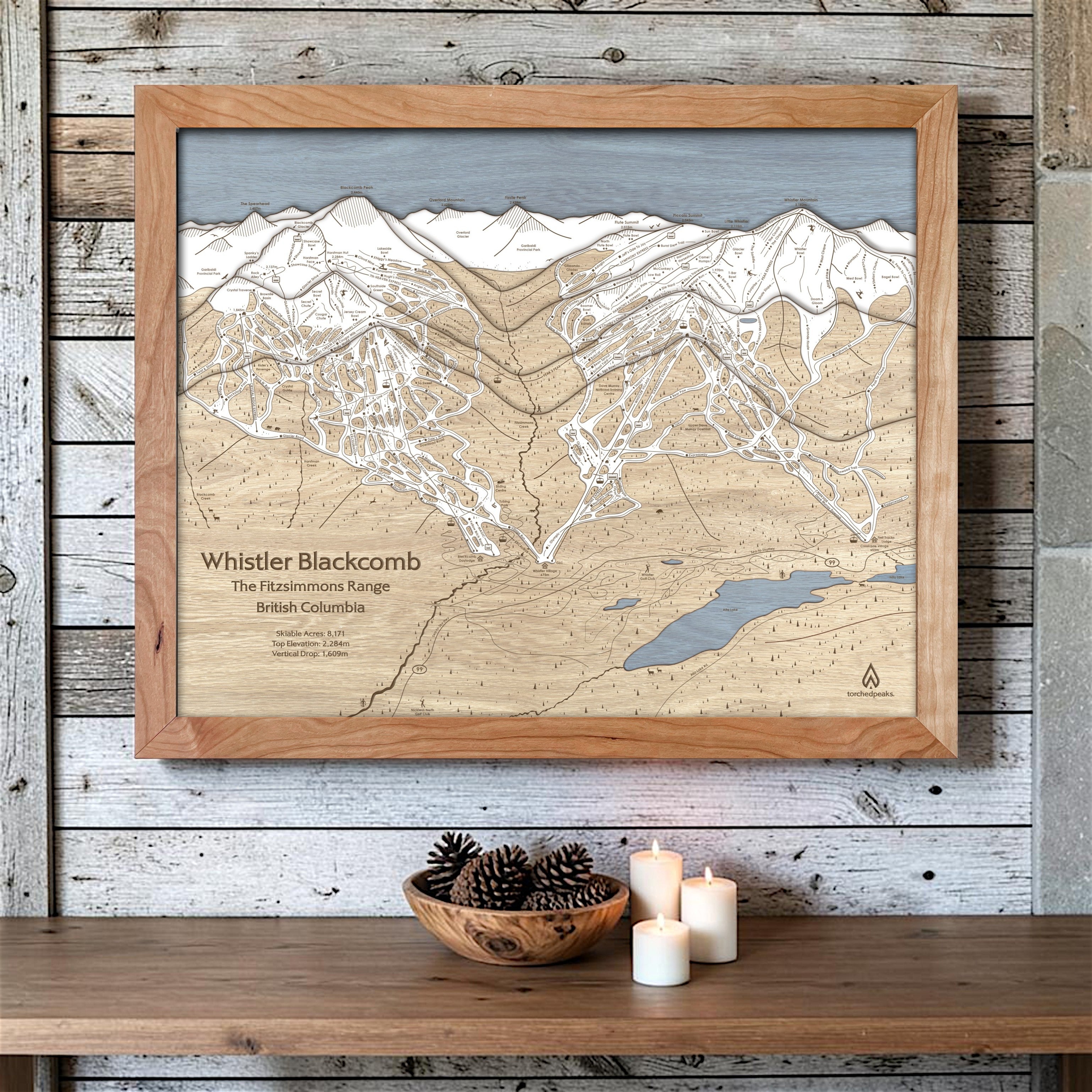 Natural-framed Whistler Blackcomb wood ski map on a whitewashed cabin wall with candles and understated mountain décor.