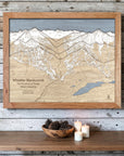 Natural-framed Whistler Blackcomb wood ski map on a whitewashed cabin wall with candles and understated mountain décor.