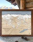 Rustic Mocha-framed Whistler Blackcomb ski map displayed on a cabin deck with snowy mountains in the distance.