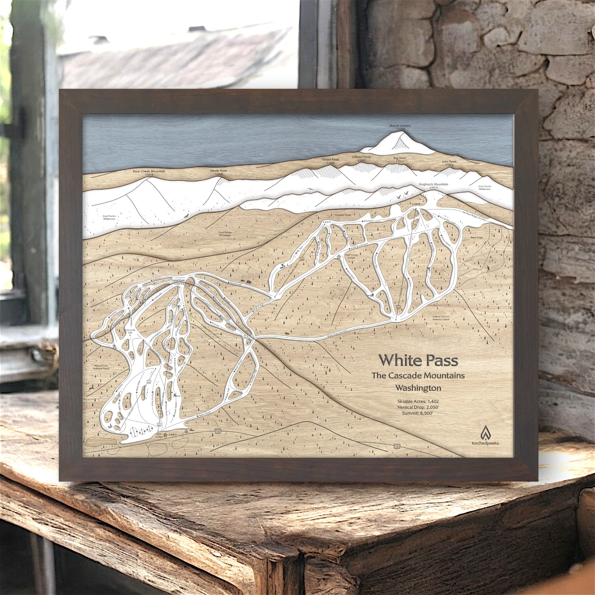 Wooden map of White Pass in the Cascade Mountains, framed and displayed on a wooden surface in a rustic ski cabin