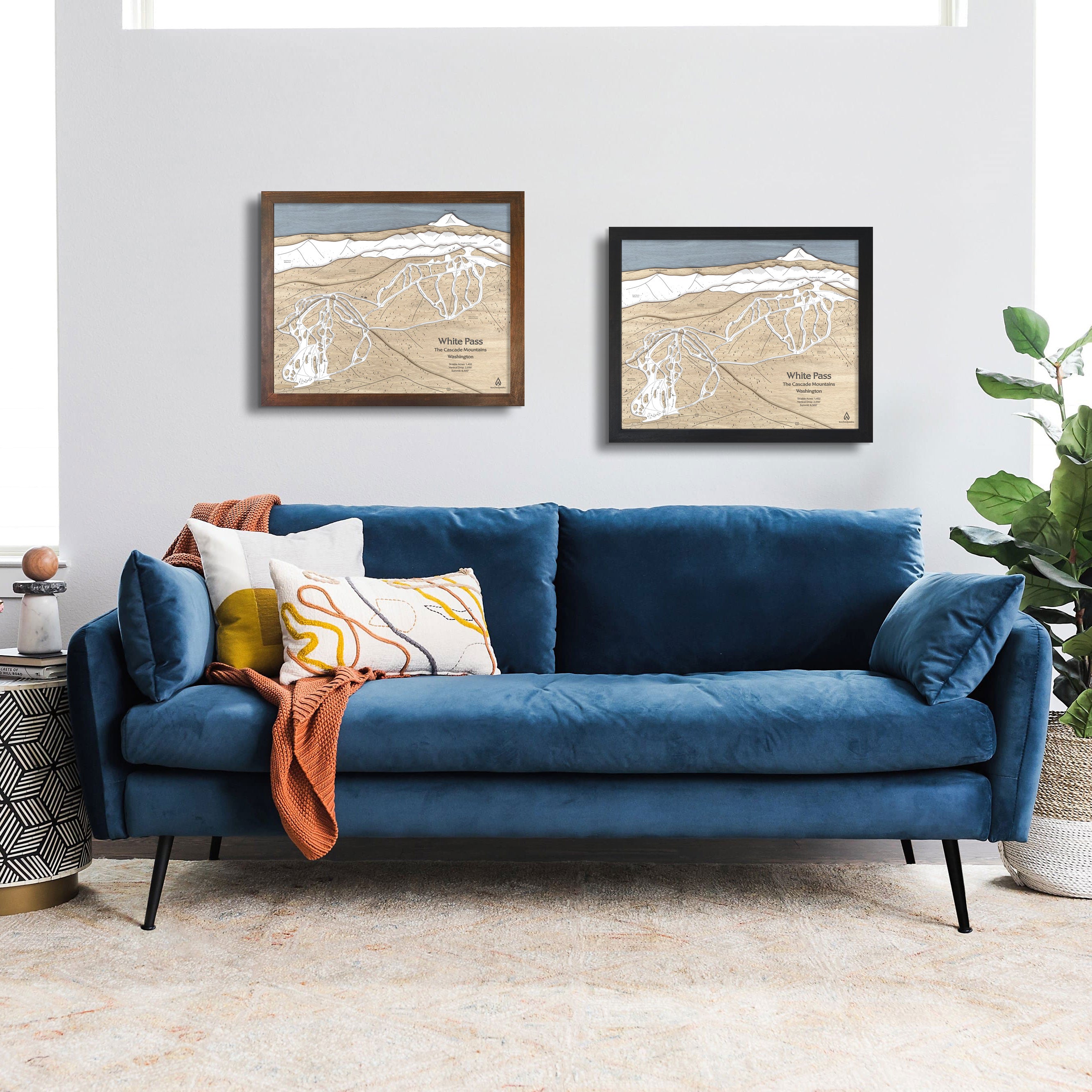 Artwork of White Pass Ski Resort displayed on a white wall above a blue sofa in a modern ski house setting. 