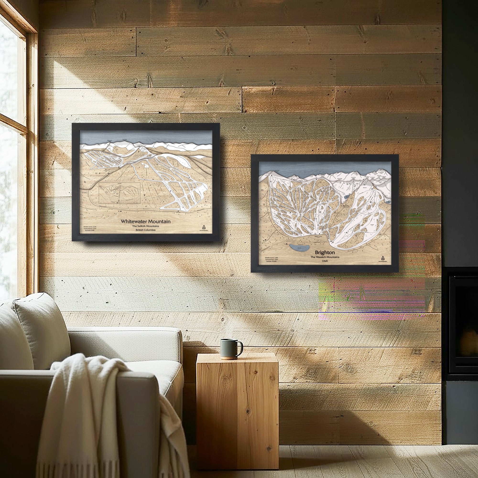 Two framed ski trail maps on a wooden wall above a sofa in a cozy ski cabin.