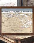 Framed wooden map of Whitewater Mountain Ski Resort in a wooden frame on a rustic surface in a rustic ski cabin. 