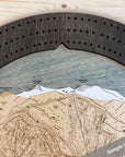 A circular wooden cribbage board game featuring a ski resort trail map in light natural wood, a birch ski slope, white snow peaks, and a matte onyx 3-player cribbage track. 