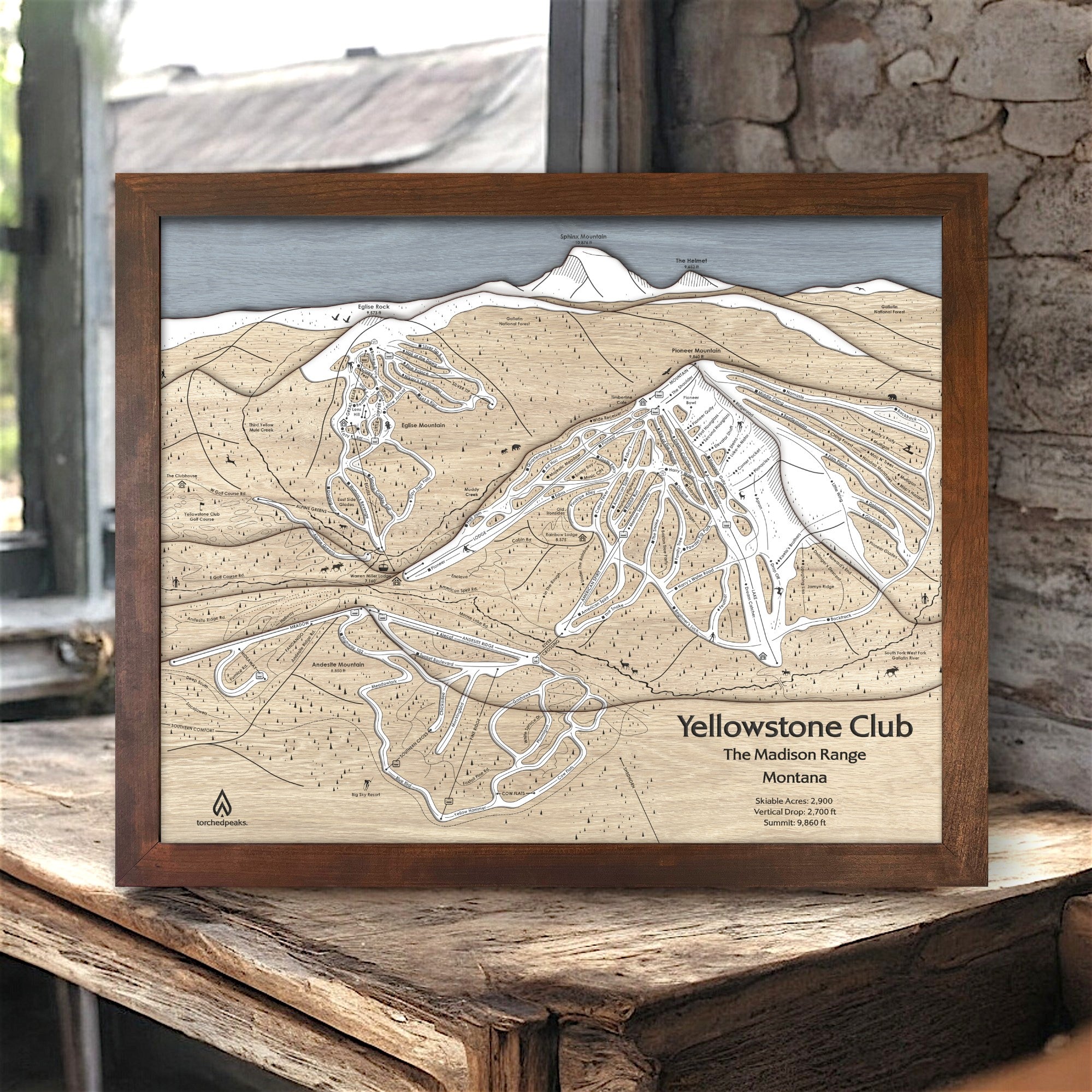 Handcrafted wooden ski map of Yellowstone Club on a rustic wooden surface in a ski cabin. 