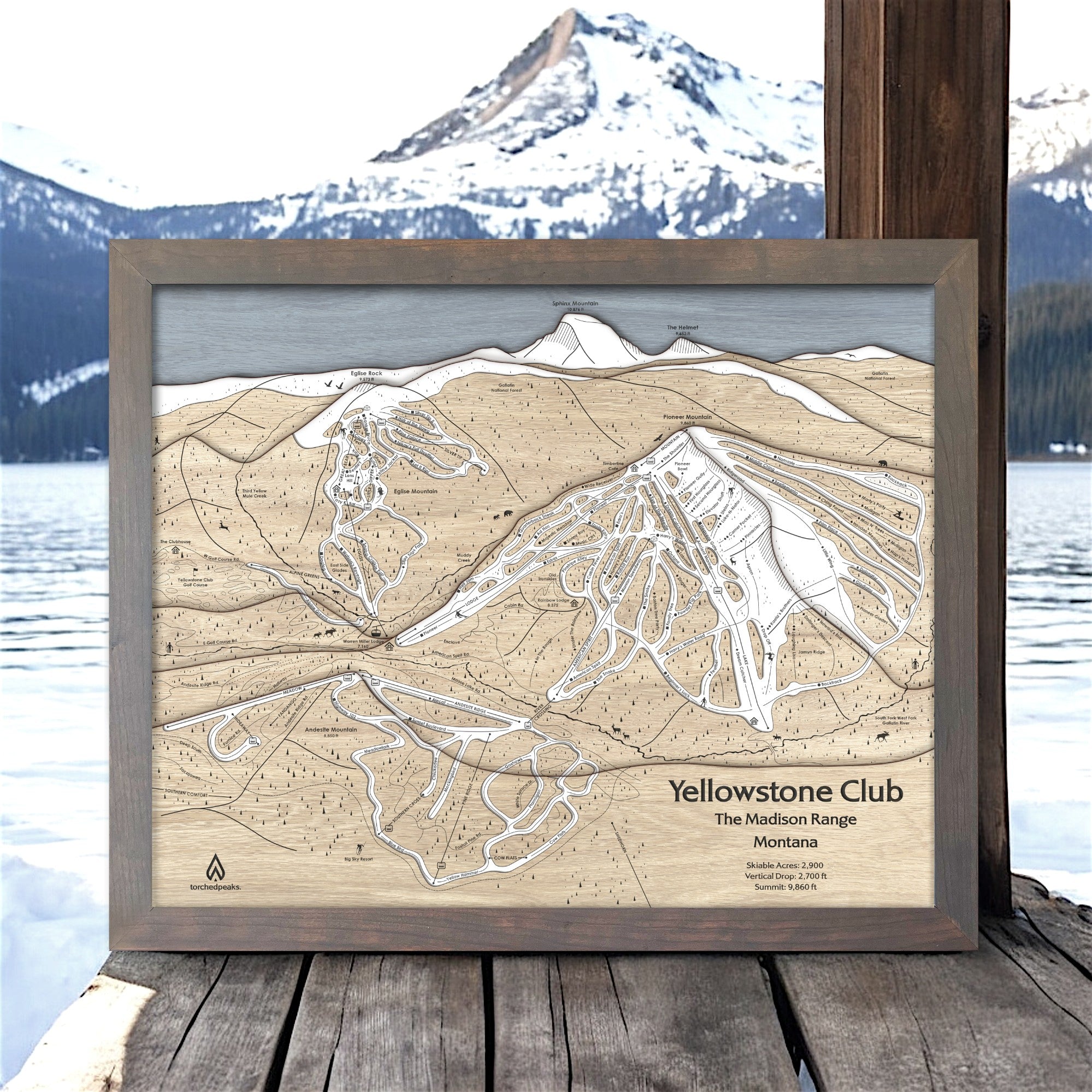Framed wooden map of Yellowstone Club ski slopes with mountainous landscape in the background