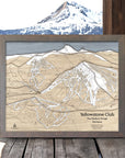 Framed wooden map of Yellowstone Club ski slopes with mountainous landscape in the background