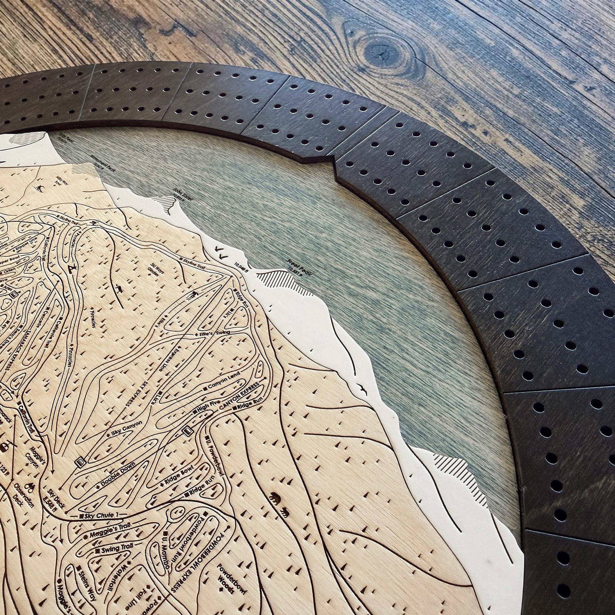 Close-up of engraved ski resort map and layered wooden cribbage board craftsmanship