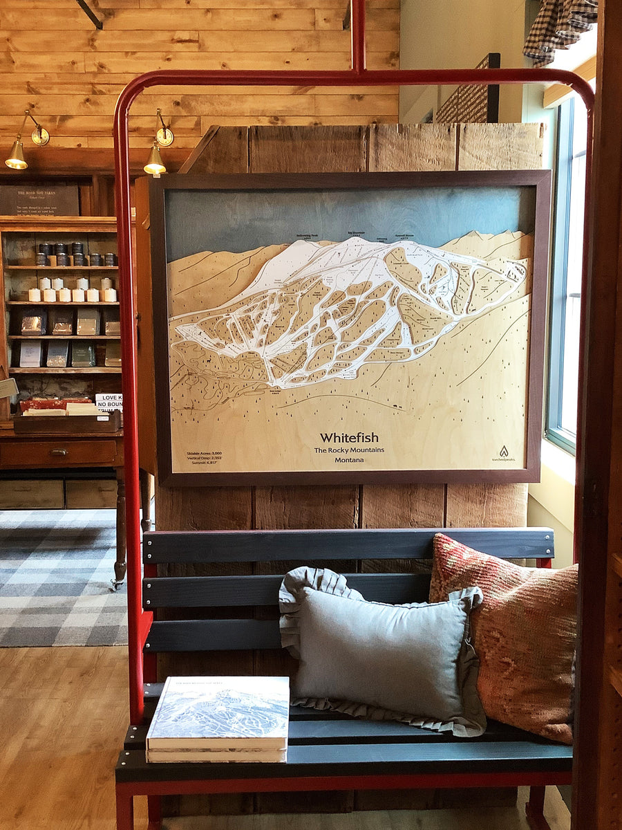 Framed map of a mountain landscape in a store setting with wooden walls and a bench.